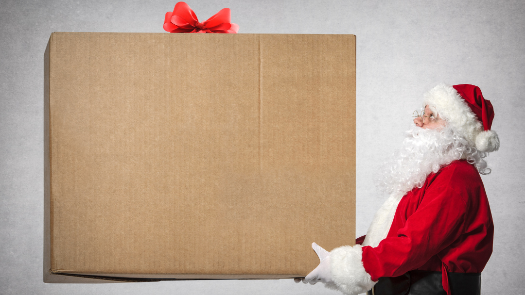 A Santa figure holding an oversized brown gift box with a red bow - Give the Gift of a Murphy Bed This Holiday Season